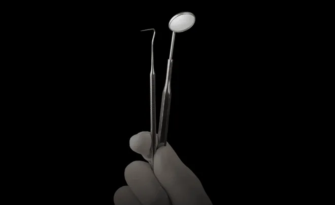 Gloved hand holding dental tools